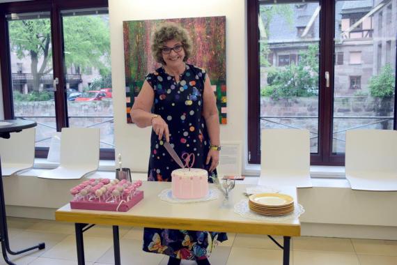 Die Vorsitzende Helmine Buchsbaum der Kinderkommission Nürnberg schneidet den Kuchen zum Jubiläum an.