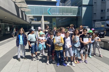 Kinder, die sich an den Ideen für den Neubau des Kinderklinikums Nürnberg beteiligen, wurden eingeladen, die Kinderklinik in Stuttgart zu besuchen. Die Gruppe von rund 20 Kindern steht vor dem Eingang des Olgahospitals.