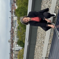 Frau Walthelm hockt vor einer Solaranlage auf dem Dach