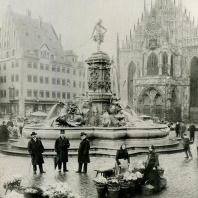 Historische Aufnahme des Neptunbrunnen auf dem Nürnberger Hauptmarkt. Im Vordergrund befindet sich ein Marktstand.