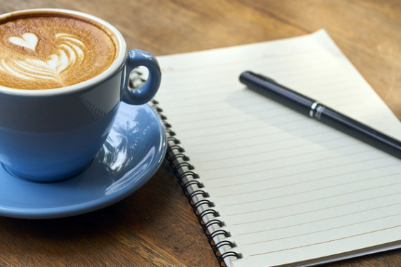 Kaffetasse und Notizblock mit Stift.