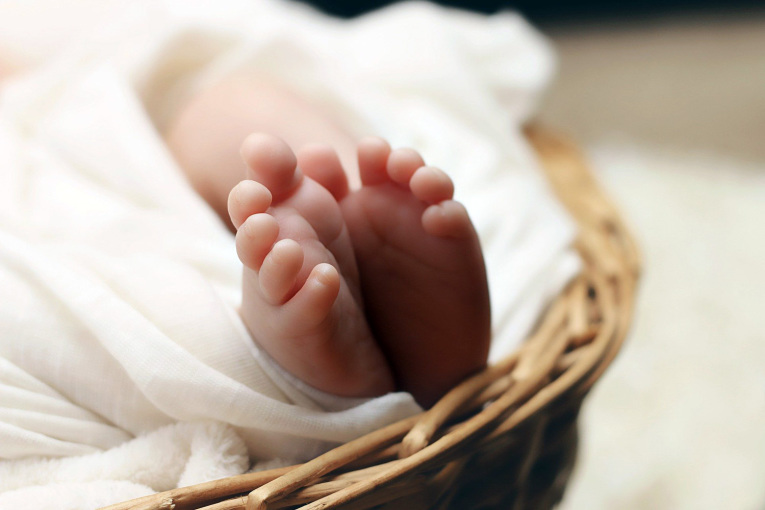 Füße eines Neugeborenen in einer Wiege.