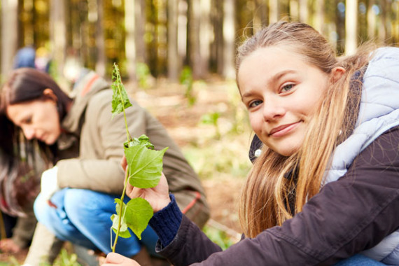 Eine junge Frau pflanzt einen Baumsetzling als Klimawandelbaum.