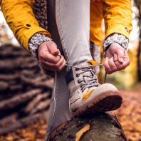Eine Frau schnürt ihre Wanderstiefel während einer Wanderung durch einen Herbstwald fester.