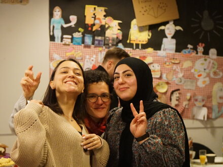 Foto von 3 fröhlichen Menschen. Hinten im Bild sieht man noch eine andere Person., Bild © ARS