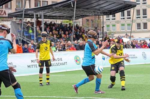 Es wird ein Fußballspiel gezeigt. Aufgrund der Gleichberechtigung werden Augenmasken getragen.
