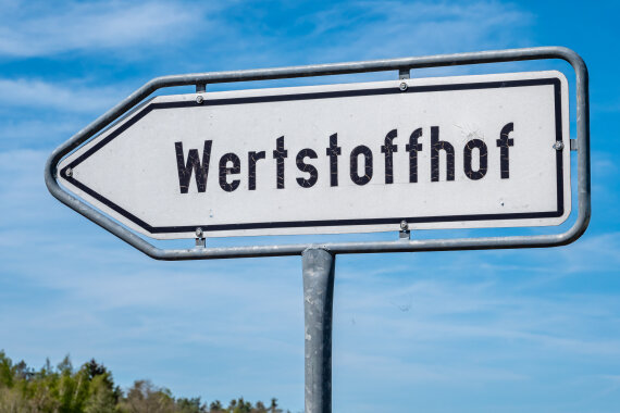 Ein Foto von einem Schild mit dem Wort: Wertstoffhof. Das Schild sieht aus wie ein Pfeil.