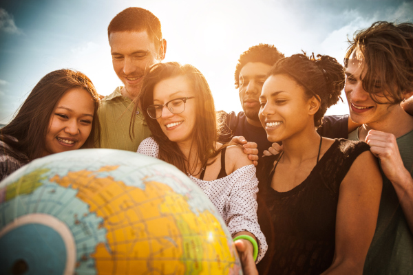 Group of friends holding an earth globe on the beach.