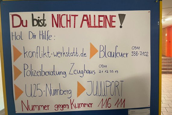 Plakat mit Hilfestellen und Telefonnummern