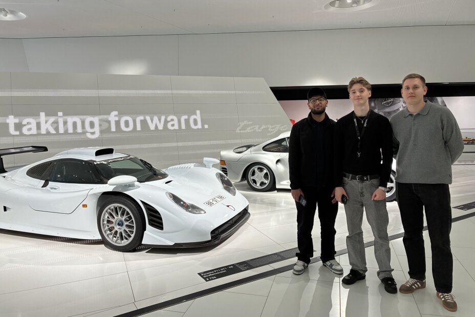 Drei Auszubildende vor einem weißen Porsche Rennfahrzeug, Bild © Berufliche Schule 4 / Stadt Nürnberg