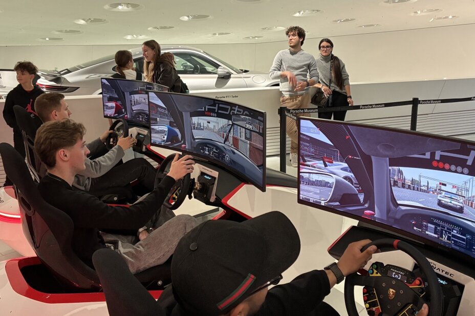 Auszubildende sitzen mit Lenkrädern vor Bildschirmen und simulieren Porschefahrten, Bild © Berufliche Schule 4 / Stadt Nürnberg