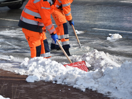 Foto von 2 Mitarbeitern vom Winter·dienst beim Schnee·räumen.