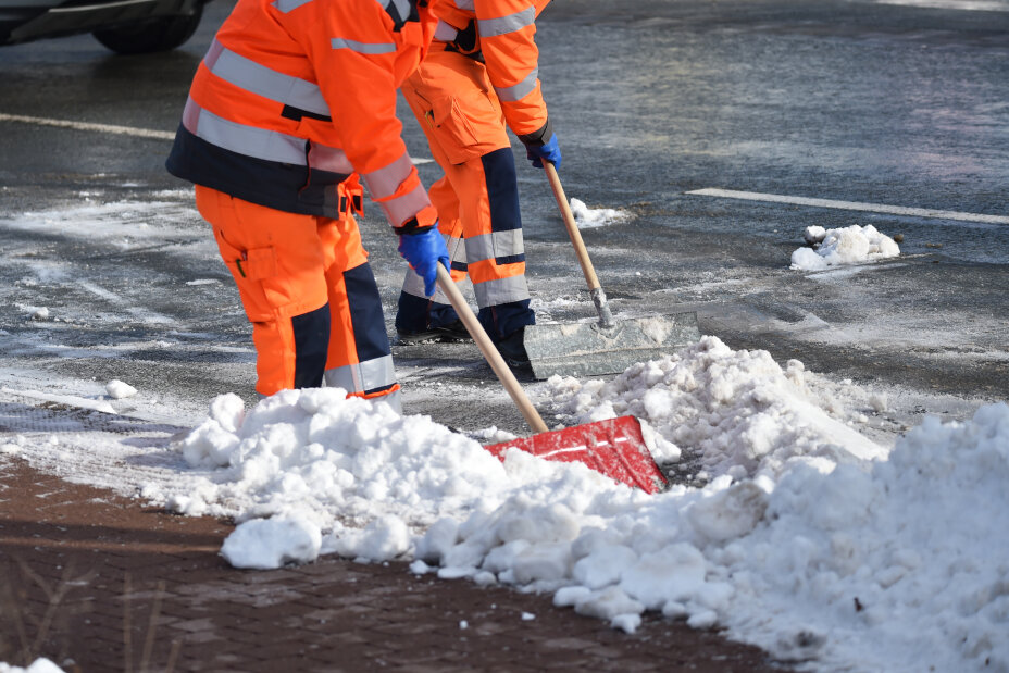 Das Bild zeigt 2 Mitarbeiter vom Winter·dienst beim Schnee·räumen.