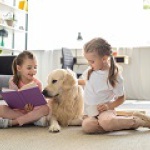 little sisters with books and golden retriever dog near by sitti
