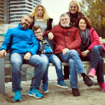 Familie mit zwei Kindern und zwei Wunschgroßeltern auf einer Bank