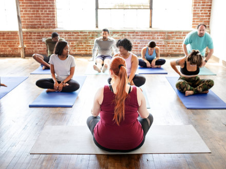 Das Bild zeigt Personen in einem Yoga-Kurs.