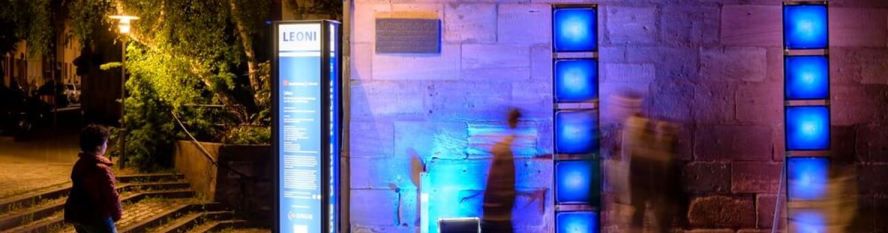 Blau beleuchtete Infostele der Blauen Nacht vor dem Herrenschießhaus.