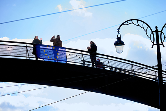 Menschen vor EU-Flagge auf einer Brücke