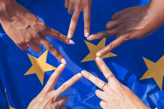 Fünf Hände formen einen Stern über einer EU-Flagge