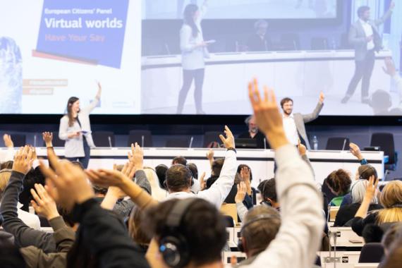 Menschen stimmen beim Bürgerforum Virtuelle Welten per Handzeichen ab