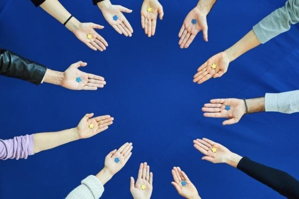 12 Hände vor einem blauen Hintergrund, die alle einen Stern auf der Handfläche liegen haben.