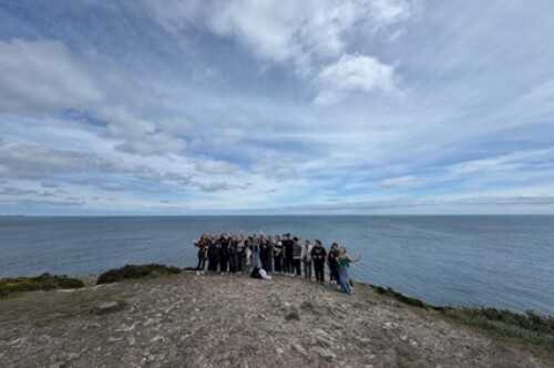 Gruppe junger Menschen steht in Irland auf einer felsigen Fläche mit dem Meer im Hintergrund © Lisa Fiona Morven Rehn