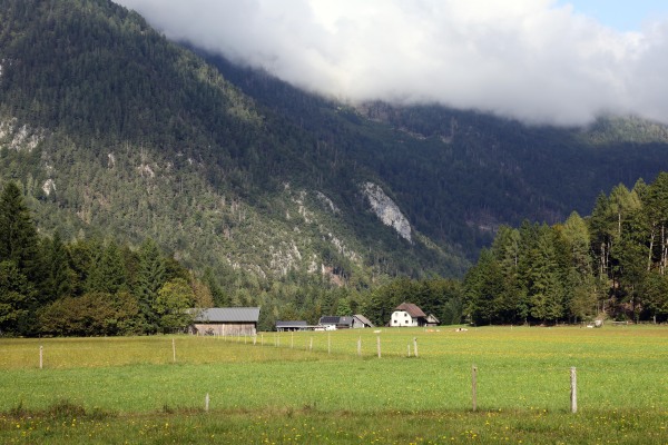 Ein paar einzelne Häuser vor einem Bergpanorama.
