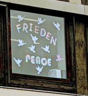 Die Wörter Frieden und Peace in bunten Buchstaben kleben in einem Fenster an der Birkenwaldschule.