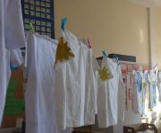 Die fertig bemalten Shirts hängen auf einer Wäscheleine im Klassenzimmer zum Trocknen.
