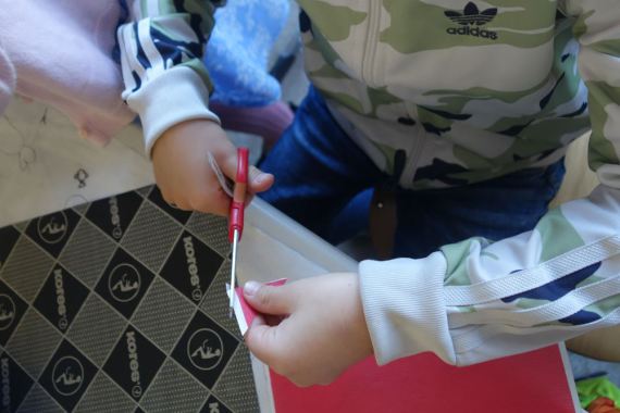 Kind schneidet Papierschnipsel für das Malen mit Hanji zurecht.