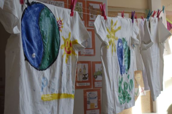 Die fertig bemalten Shirts hängen auf einer Wäscheleine im Klassenzimmer zum Trocknen