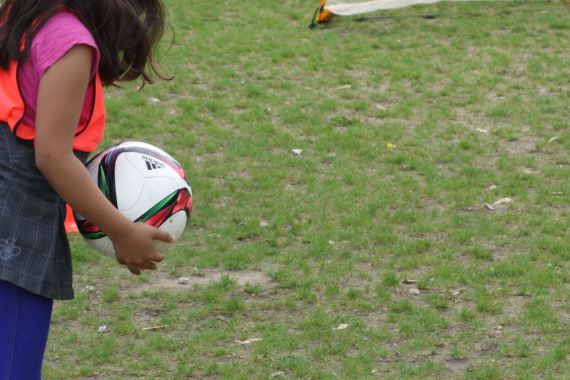 Ein Mädchen wirft einen Fußball von der Seitenlinie ein