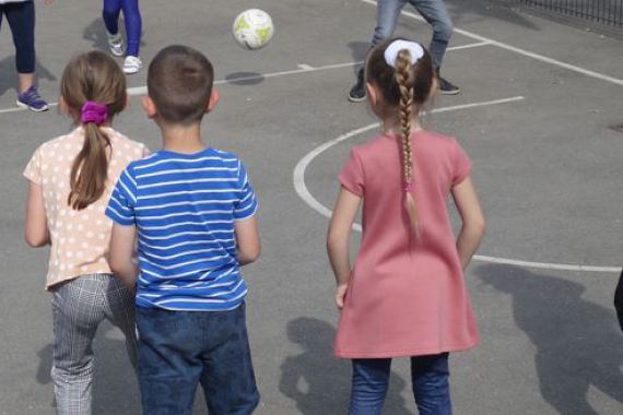 Kinder spielen sich einen Fußball gegenseitig zu.