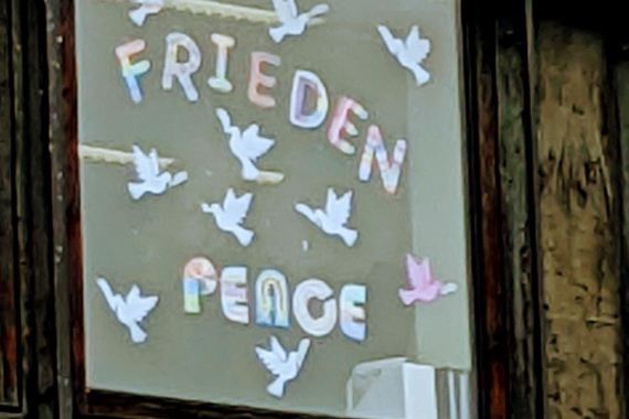 Die Wörter Frieden und Peace in bunten Buchstaben kleben in einem Fenster an der Birkenwaldschule.