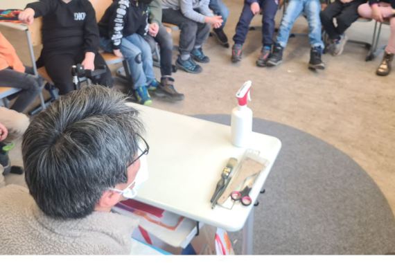 Künstler Changhee Nam erklärt den Kindern seine Maltechnik in einem Stuhlkreis.