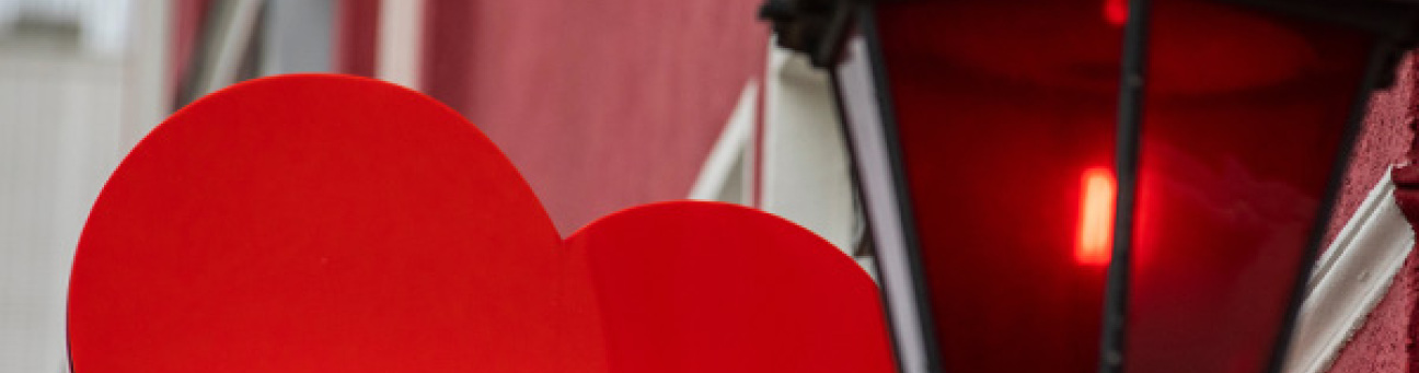 Rotes Herz als Werbeschild neben einer roten Laterne an einer Hausfassade., Bild © bilderstoeckchen / stock.adobe.com