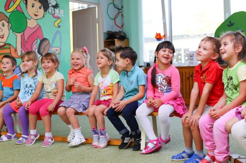 Kinder sitzen auf Turnbank.