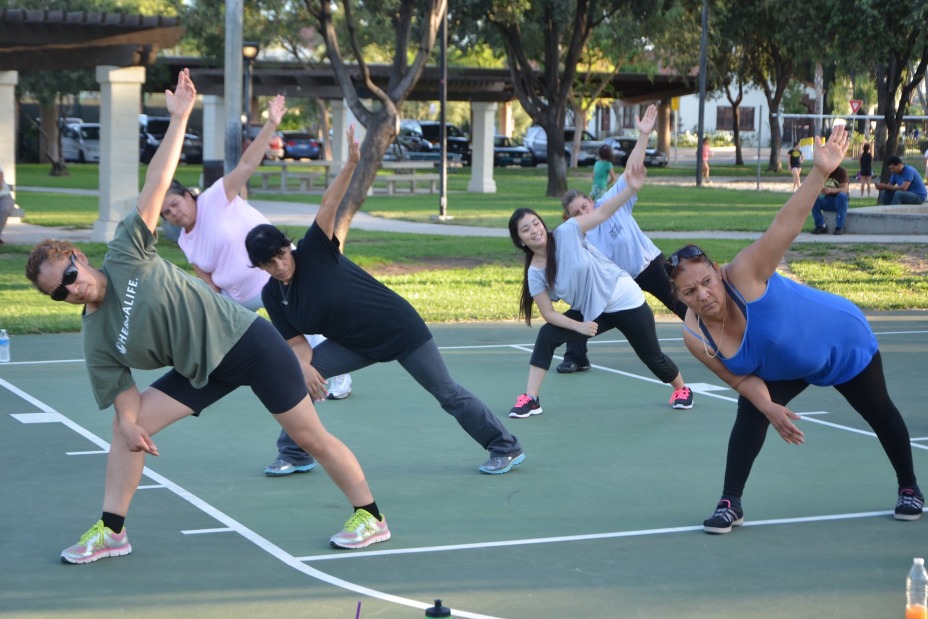 Menschen machen Dehnübungen auf einem Sportplatz im Freien., Bild © Pixabay