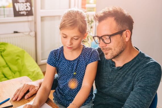 Vater und Tochter benutzen bei den Hausaufgaben ein Tablet