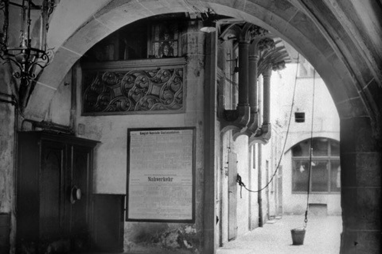 Blick in den Innenhof mit Laubengang und Kreuzgewölbe, im Mittelgrund ein Fahrplan der Königlich bayerischen Staatseisenbahnen und ein dösender Hund, Bild © Unbekannter Fotograf des Photographischen Klubs Nürnberg, 1912. (StadtAN A 43 Nr. P-79-10) Sommerausstellung Stadtarchiv 2, Bild © Unbekannter Fotograf des Photographischen Klubs Nürnberg, 1912. (StadtAN A 43 Nr. P-79-10)