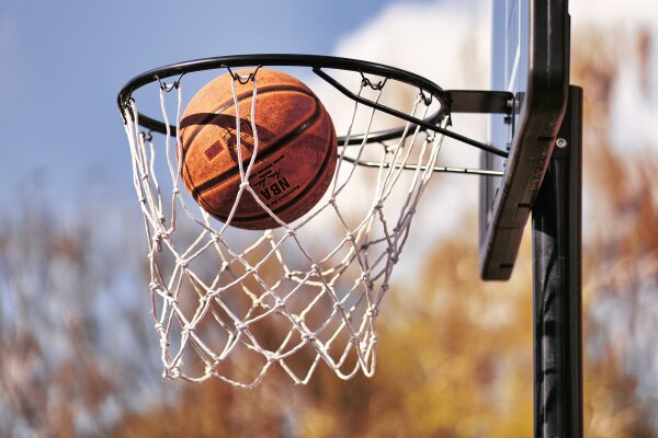 Ein Basketball liegt im Netz eines Basketballkorbs