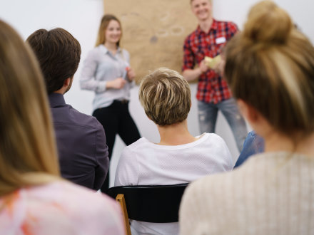 Foto von Männern und Frauen bei einem Vortrag., Bild © Adobe Stock