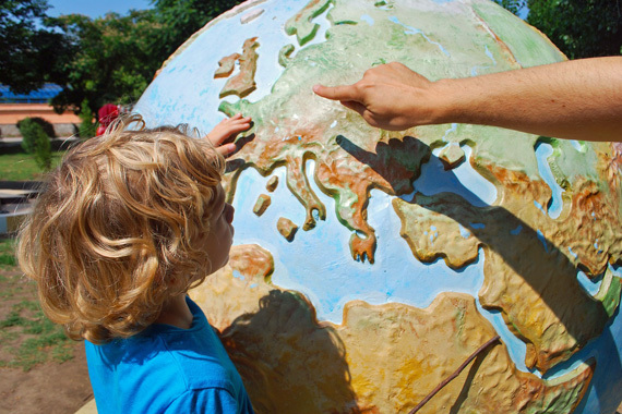 Ein Mann zeigt einem Kind die Erde auf einem großen Globus.