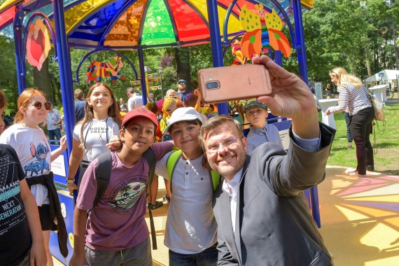 Kinder machen Selfies mit Oberbürgermeister Marcus König vor dem Regenbogenpavillion der zehnten Station