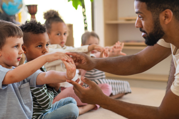Ein junger Erzieher spielt mit Kinder in einer Kindertageseinrichtung.