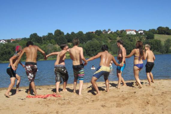 Jugendlichen halten sich an den Händen und laufen ins Wasser