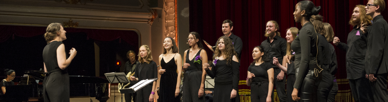 Jugendchor in schwarzer Konzertkleidung vor rotem Samtvorhang des Opernhauses.