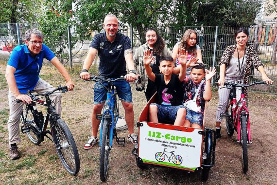 Spendenübergabe auf Fahrrädern mit dem IJZ Team, vier Kindern un