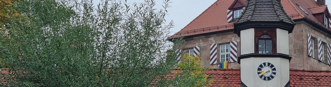 Abbildung des Türmchens vom Eingangsbereich im Torbogen des Zeltnerschlosses mit Banner "50 Jahre Kulturläden" und Bäumen im Hintergrund.