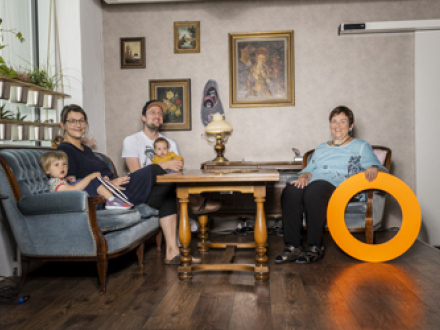 Foto von Menschen an einem Tisch. Links auf einem Sofa sitzen eine Frau und ein Mann mit 2 kleinen Kindern. Rechts auf einem Sessel sitzt eine ältere Frau., Bild © Stadt Nürnberg / Amt für Kultur und Freizeit